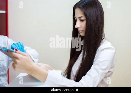 Junges Mädchen an der Arztaufnahme, der Patient füllt ein Formular in der Klinik aus Stockfoto