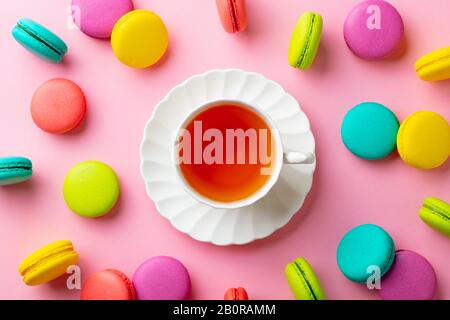 Makronen Dessert und Tasse Tee auf pinkfarbenem Pastellhintergrund. Draufsicht. Stockfoto