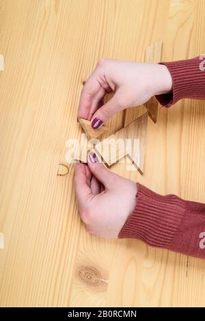 Mädchen sammelt auf einem Holztisch ein Holz-Tangram-Puzzle. Chinesisches Tangram-Puzzle. Puzzle-Konzept. Stockfoto