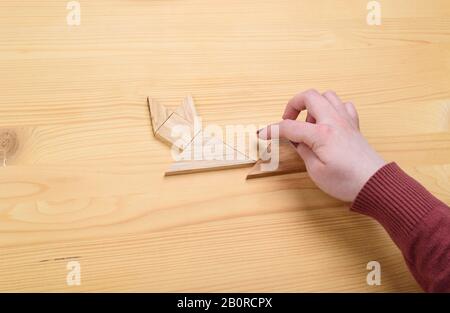 Mädchen sammelt auf einem Holztisch ein Holz-Tangram-Puzzle. Chinesisches Tangram-Puzzle. Puzzle-Konzept. Stockfoto