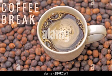 Tasse cremigen Kaffees in der Mitte der Bohnen, die auf der Lasche verstreut sind Stockfoto