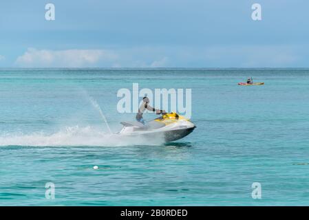 Valley Church Bay, Antigua und Barbuda - 18. Dezember 2018: Young Man on Personal Watercraft (Water Scooter) at the Tropical Valley Church Beach in Th Stockfoto