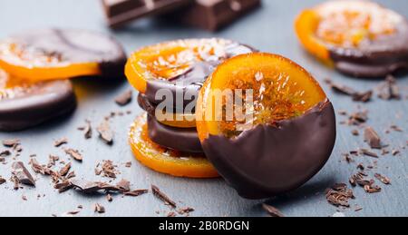 Kandierte Orangenscheiben in der Schokolade. Schiefer Hintergrund. Close Up. Stockfoto