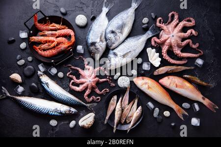 Frisches Fisch- und Meeresfrüchte-Sortiment auf schwarzem Schiefergrund. Draufsicht. Stockfoto