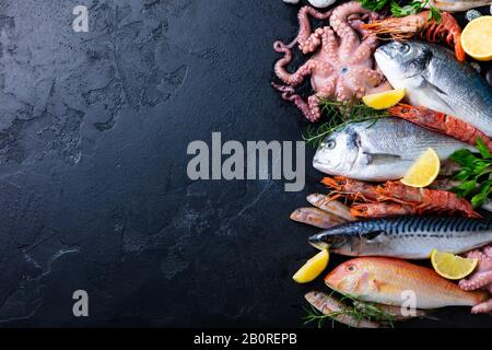 Frisches Fisch- und Meeresfrüchte-Sortiment auf schwarzem Schiefergrund. Draufsicht. Kopierbereich. Stockfoto