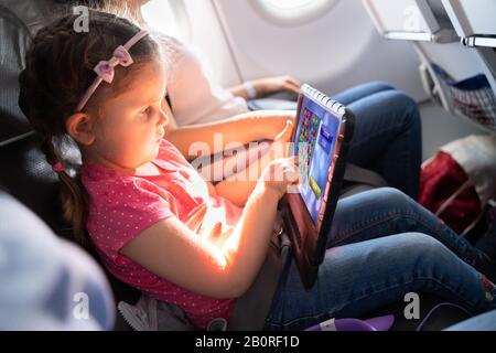 Adorable Little Girl Mit Digital Tablet Auf Reisen Mit Dem Flugzeug Stockfoto