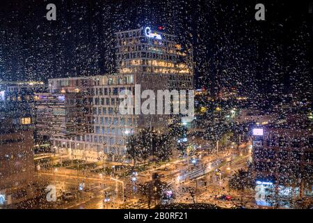 Bild einer Stadt Nacht Lichter durch das große Fenster in einer regnerischen Nacht aufgenommen. Stockfoto