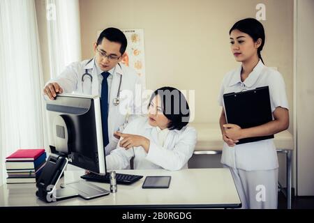 Eine Gruppe von Ärzten, die sich auf der Station des Krankenhauses mit einem Computer treffen. Stockfoto