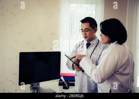 Zwei Ärzte diskutieren über Arbeit. Während Sie gemeinsam im Krankenhaus durch das Tablett schauen. Stockfoto