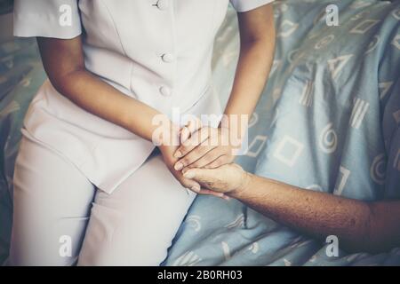 Nahaufnahme der Jungen Krankenschwester: Achten Sie auf ältere Patienten, die sie halten, und fühlen Sie sich während der Aufnahme im Krankenhaus wohl. Stockfoto