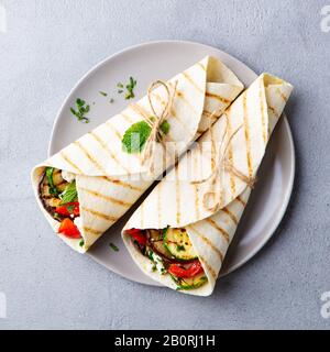 Legen Sie das Sandwich mit gegrilltem Gemüse und Fetakäse auf einen Teller. Grauer Hintergrund. Draufsicht Stockfoto