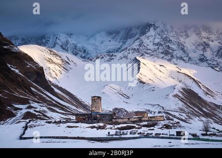 Wachtturm vor einer Bergkulisse bei Sonnenaufgang, Ushguli, Upper Svanetia, Georgia Stockfoto