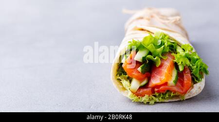 Sandwiches einwickeln, mit Fischlachs und Gemüse rollen. Grauer Hintergrund. Nahaufnahme. Stockfoto