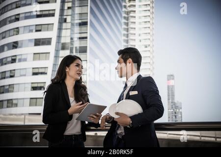 Die Kollegen im Unternehmen sehen sich die Arbeit im Tablet zusammen an. Stockfoto