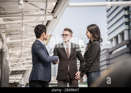 Geschäftspartner schütteln die Hände und lächeln, während sie sich vor dem Büro treffen. Geschäfts- und Erfolgskonzept. Stockfoto