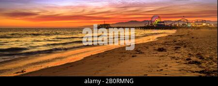 Santa Monica Historic Landmark, Kalifornien, Vereinigte Staaten. Wundervolle Landschaft des berühmten Santa Monica Pier am orangefarbenen roten Sonnenuntergang vom Strand an Stockfoto