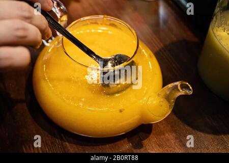 Vitamin gesunder Meeresbuckdorntee in einer kleinen Glaskanne mit frischen rohen Sanddornbeeren und Zimtstäbchen, Kochvorgang. Stockfoto
