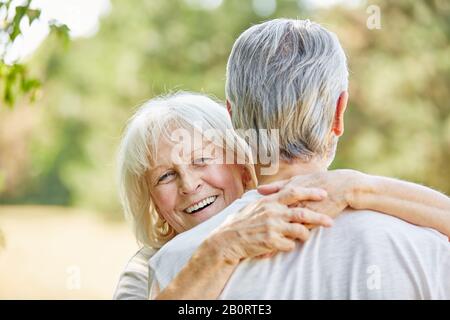 Lachende alte Frau umarmt im Sommer den Mann in der Natur Stockfoto