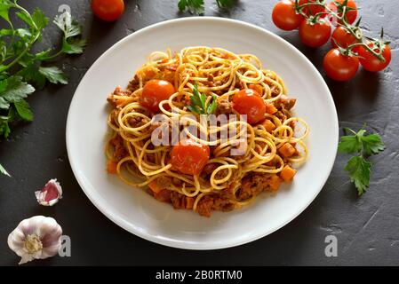 Nahaufnahme von Spaghetti mit Hackfleisch und Kirschtomaten auf schwarzem Steingrund. Stockfoto