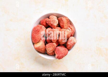 Getrocknete Erdbeeren in der Schüssel über hellem Steingrund. Dehydrierte Erdbeeren. Draufsicht, flacher Lay Stockfoto