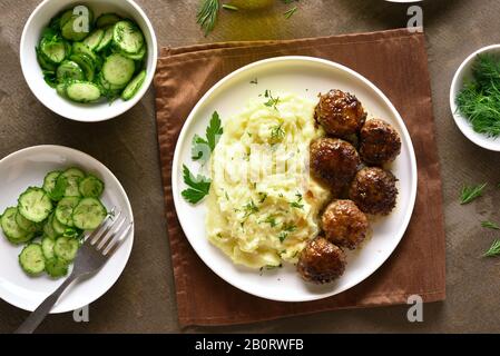 Hackfleisch Schnitzel mit Kartoffelbrei auf weißen Platte über braunen Hintergrund. Ansicht von oben, flach Stockfoto