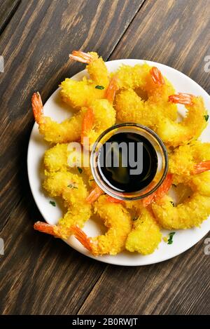 Frittierte panierte Garnelen mit Soße auf dem Teller auf Holztisch. Draufsicht, flacher Lay Stockfoto