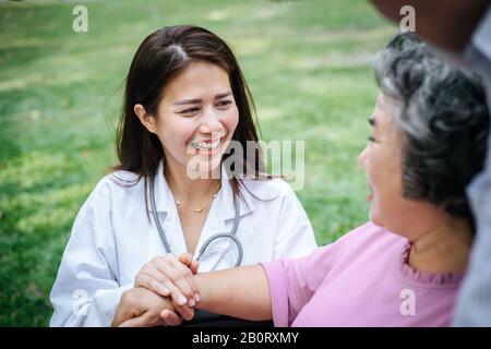 Pflegekraft, die ältere Patienten im Rollstuhl betrachtet. Arzt spricht mit alten Behinderten Stockfoto