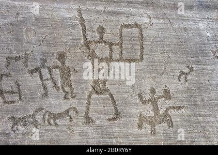 Petroglyph-Felsschnitzerei, von zwei Kriegern mit Schild und einem Mann, der ein Pferd reitet. Geschnitzt von der alten Camunni Foppi di Nadro, Riserva Naturale Incis Stockfoto
