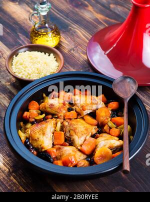 Tagine mit gekochtem Huhn und Gemüse. Brauner Holzhintergrund. Stockfoto