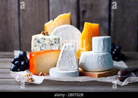 Käsesortiment: Blaukäse, Hartkäse, Weichkäse auf Pergamentpapier. Holzhintergrund. Stockfoto
