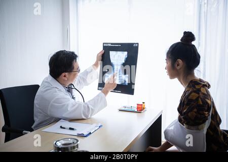 Der Arzt erklärt über die Brain-X-ray-Ergebnisse zu einer Patientin im Bett liegend an einem Krankenhaus Stockfoto