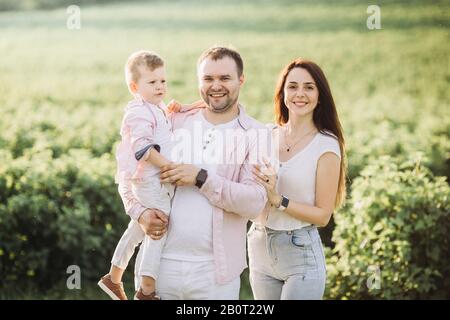 Glückliche Familie, die auf einem grünen Feld posiert Stockfoto