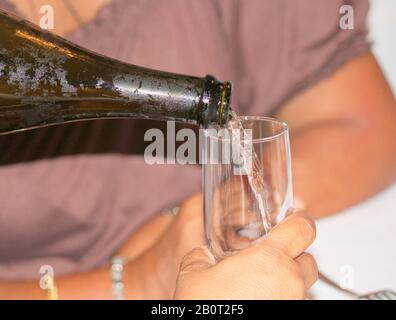 Champagner, der aus der Flasche in ein Glas gegossen wird Stockfoto