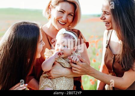 Drei Generationen. Großmutter, Töchter und Enkelin auf einer grünen Wiese. Stockfoto