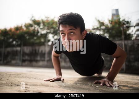 Nahbild eines jungen Sportlers, der draußen Push-ups macht Stockfoto