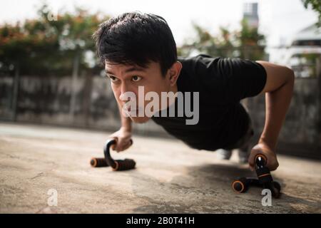 Nahbild eines jungen Sportlers, der draußen Push-ups macht Stockfoto