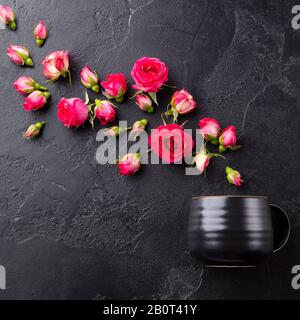 Teetasse mit frischen Rosen Blumen auf schwarzem Steingrund. Draufsicht. Kopierbereich. Stockfoto