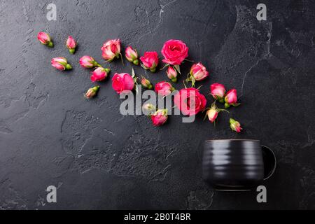 Teetasse mit frischen Rosen Blumen auf schwarzem Steingrund. Draufsicht. Kopierbereich. Stockfoto