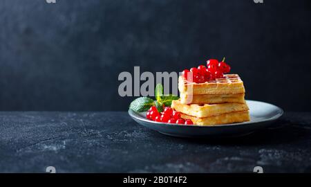 Belgische Waffeln mit frischen roten Himbeeren. Dunkler Schieferhintergrund. Kopierbereich. Stockfoto