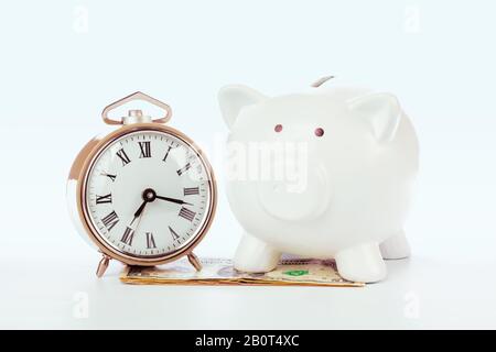 Piggy Bank mit Uhr auf dem Geldhaufen. Kreatives Foto. Stockfoto