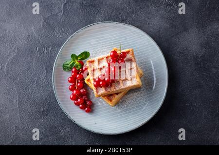 Belgische Waffeln mit frischen roten Himbeeren. Grauer dunkler Hintergrund. Draufsicht. Stockfoto