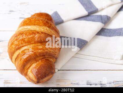 Französisches Rosy Croissant auf hellem Serviette auf weißem Hintergrund. Backwarenkonzept. Stockfoto