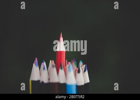 Roter Bleistift, der das Konzept des Stehens aus der Masse darstellt