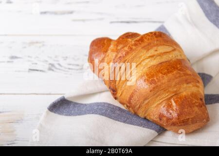 Französisches Rosy Croissant auf hellem Serviette auf weißem Hintergrund. Backwarenkonzept. Stockfoto