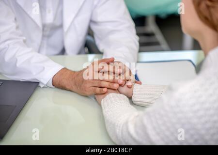 Nahaufnahme der männlichen Hände, die die Hände des Patienten halten Stockfoto