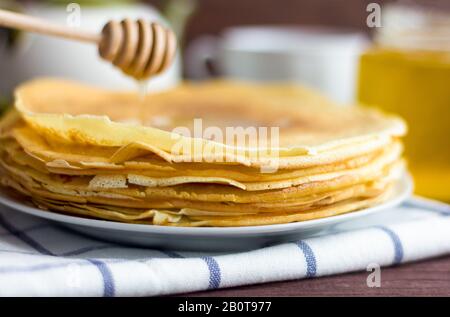 Frisch gebackene Pfannkuchen mit Honig auf einem Teller. Traditionelle hausgemachte Kuchen. Maslenitsa. Stockfoto