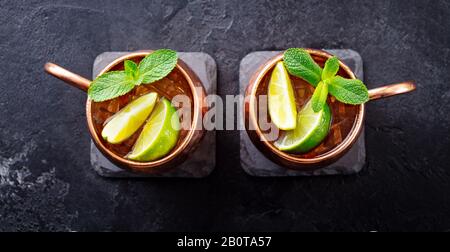 Cold Moscow Mules Cocktail mit Ingwerbier, Wodka, Limette und Minze. Grauer Steinhintergrund. Draufsicht. Stockfoto