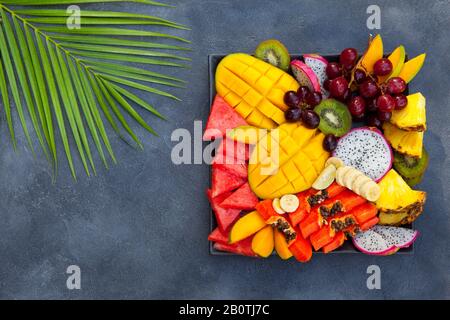 Tropische Früchte auf einem Teller. Grauer Hintergrund. Kopierbereich. Draufsicht. Stockfoto