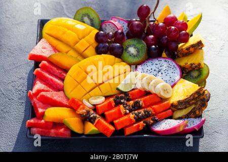 Tropische Früchte auf einem Teller. Grauer Hintergrund. Nahaufnahme. Stockfoto