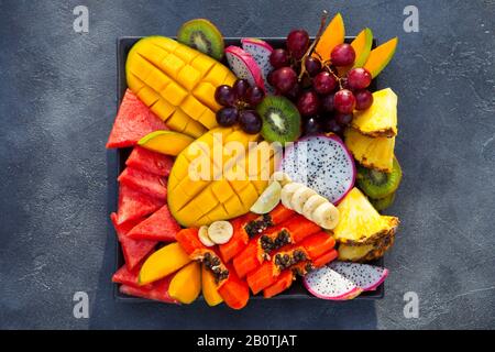 Tropische Früchte auf einem Teller. Grauer Hintergrund. Nahaufnahme. Draufsicht. Stockfoto